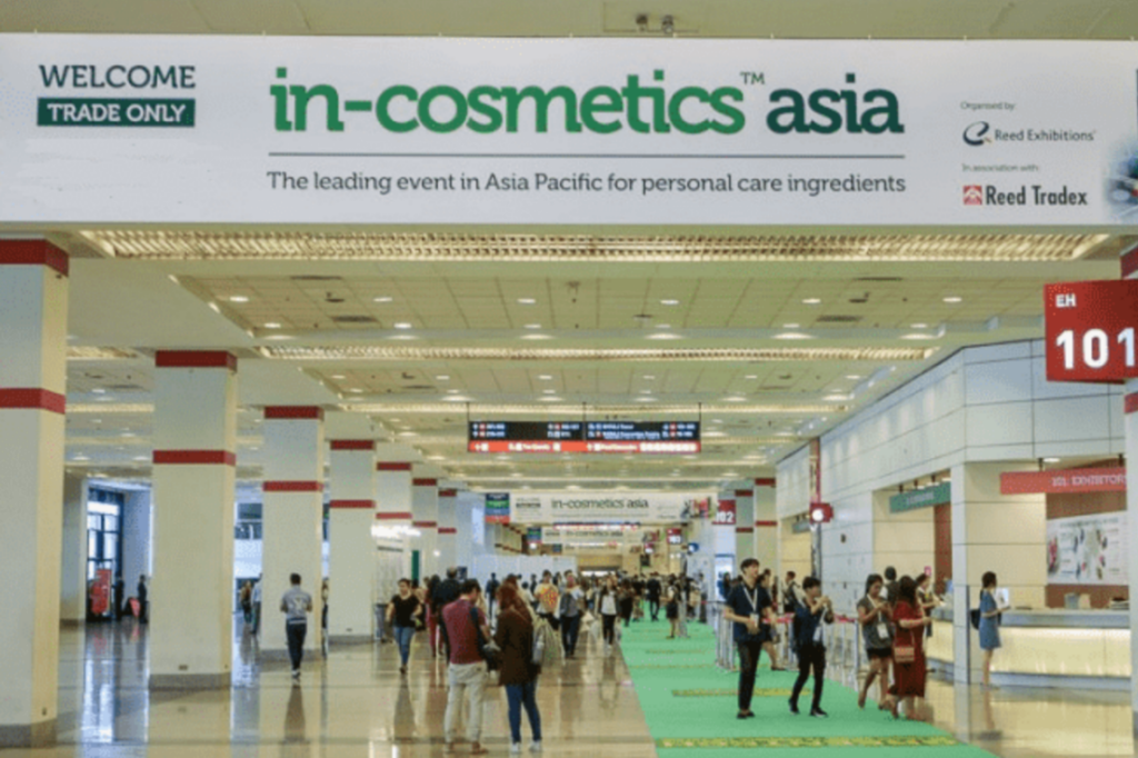Entrance hall at in-cosmetics asia trade show with attendees walking beneath event signage